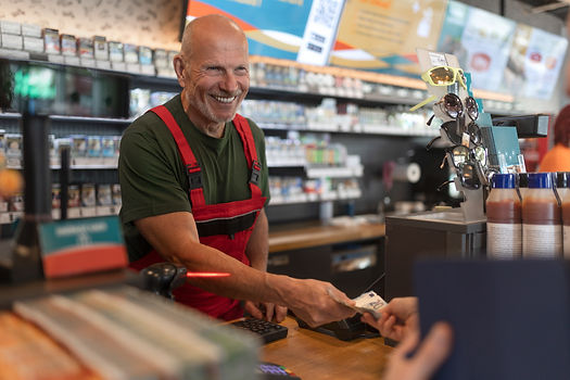 A cashier in accepting cash in a gas station convenience store that uses a cash recycler under the counter.